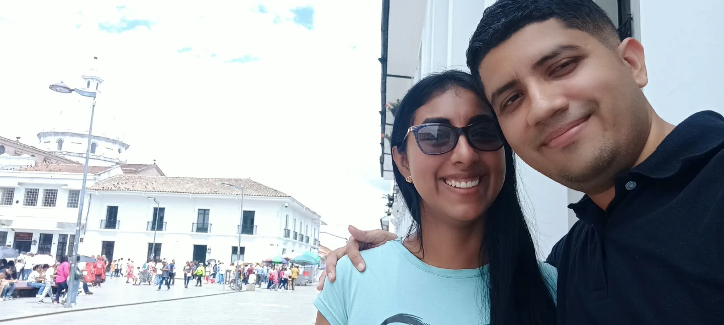 Jors y Yanet abrazados para una foto frente a una plaza